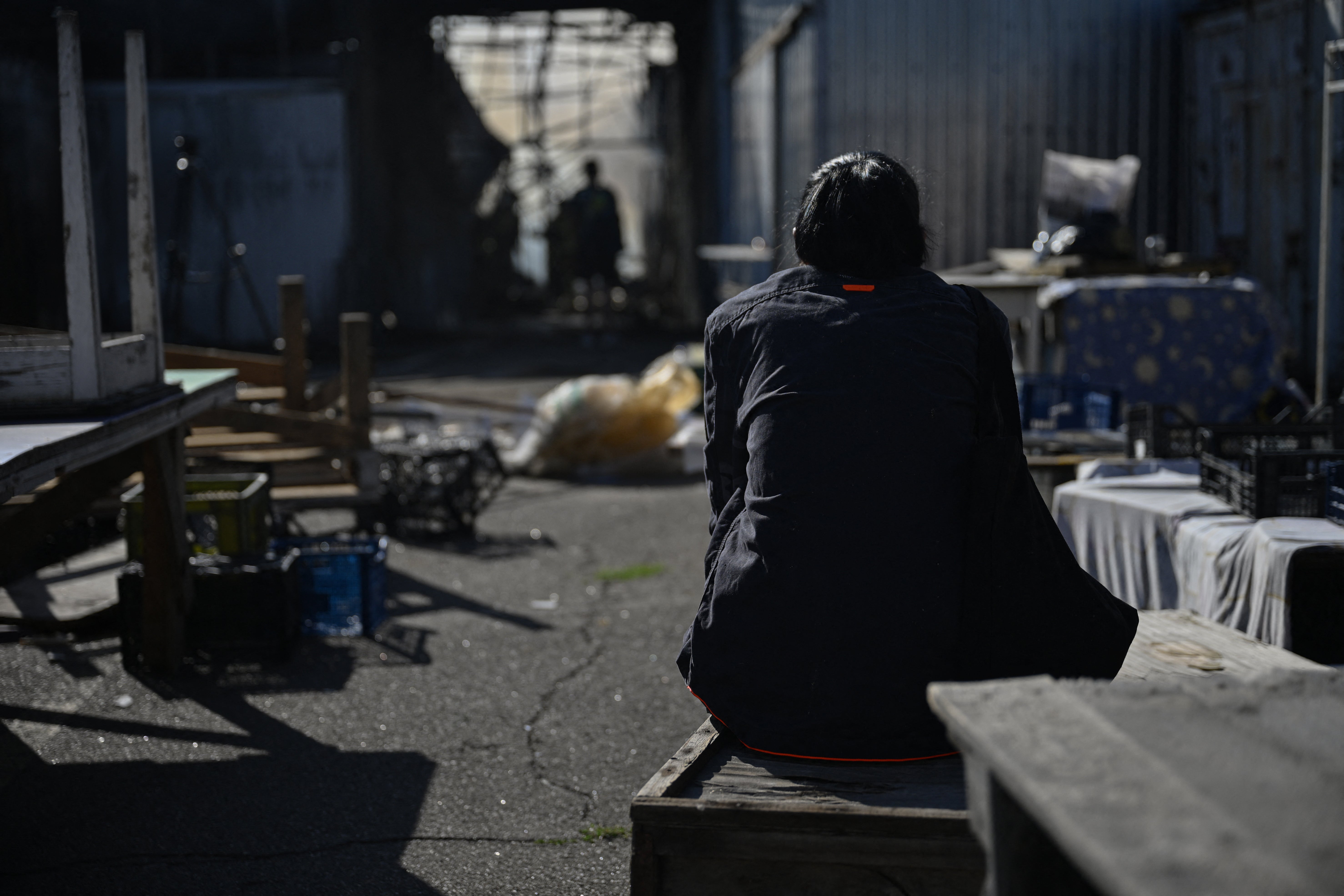 A Ukrainian vendor sits amidst the damage caused by a strike on a market in Kyiv