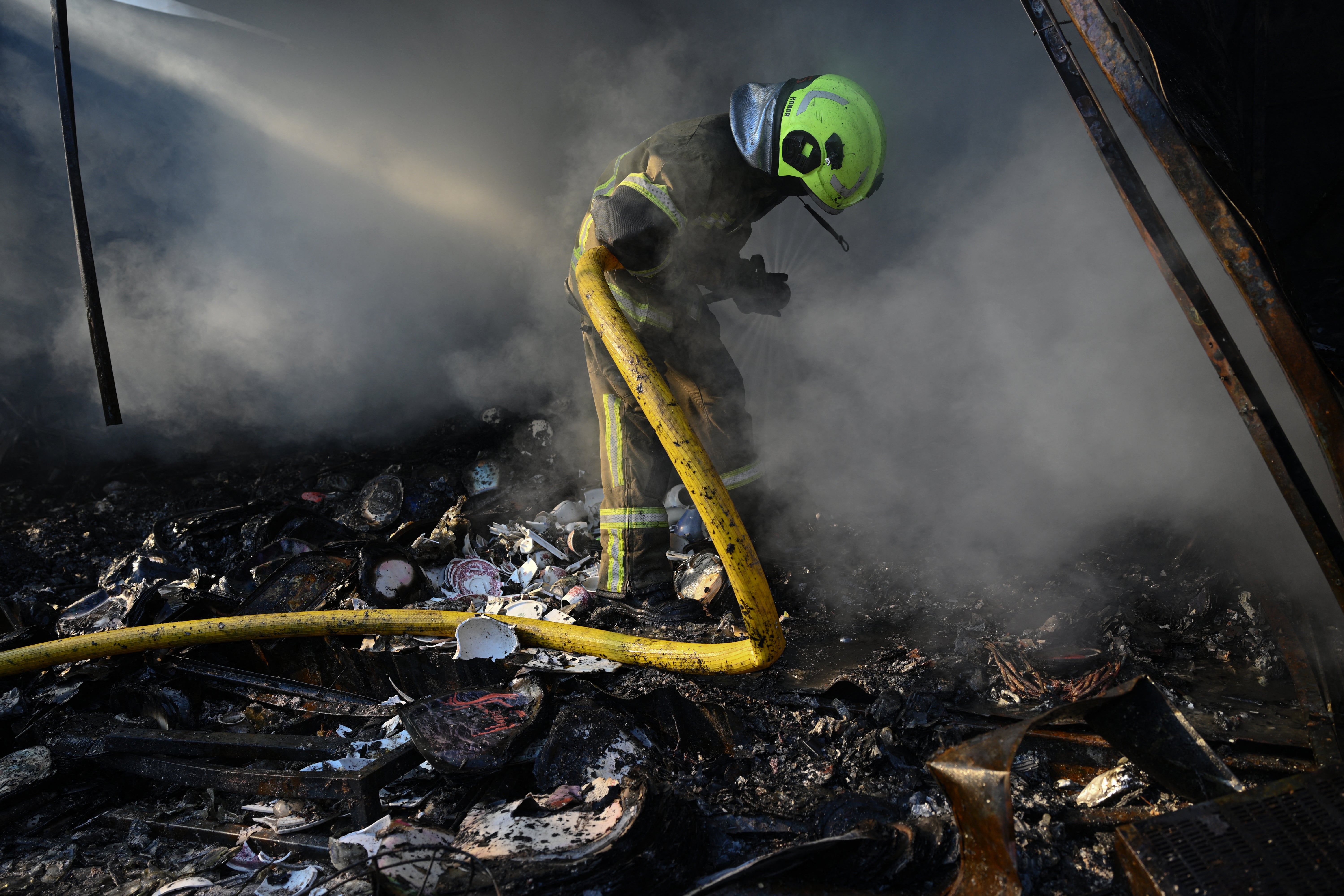 A Ukrainian firefighter works to extinguish a fire caused by the Russian attacks