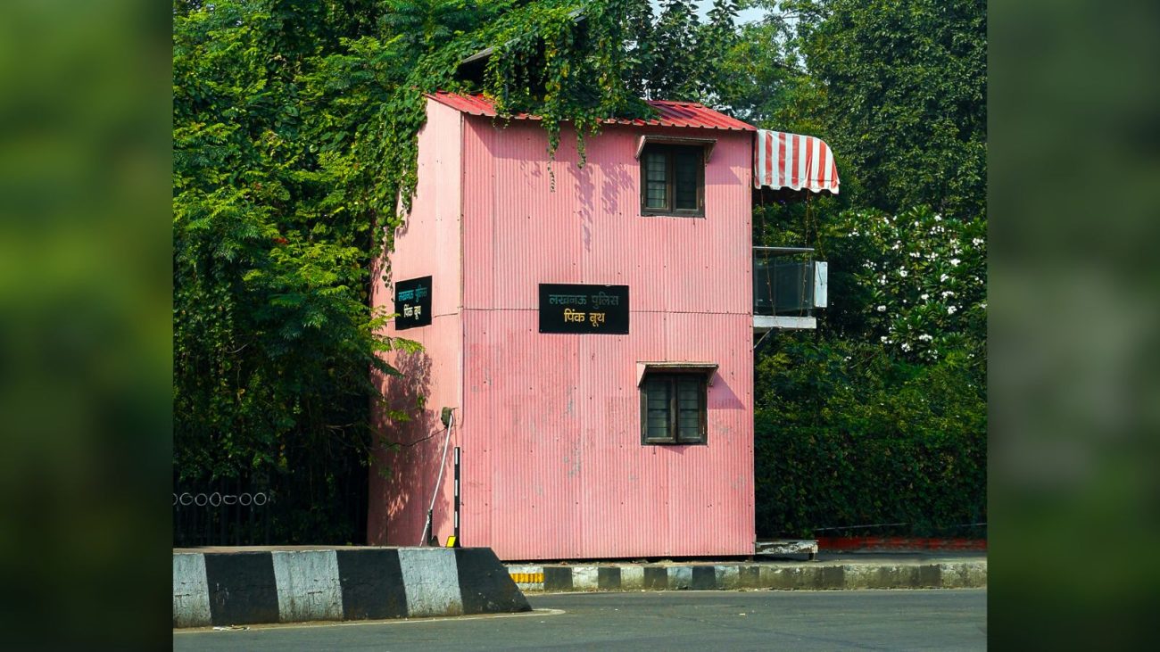 Casa vertical estreita e compacta pintada de rosa com telhado vermelho, localizada à beira da rua e cercada por vegetação densa