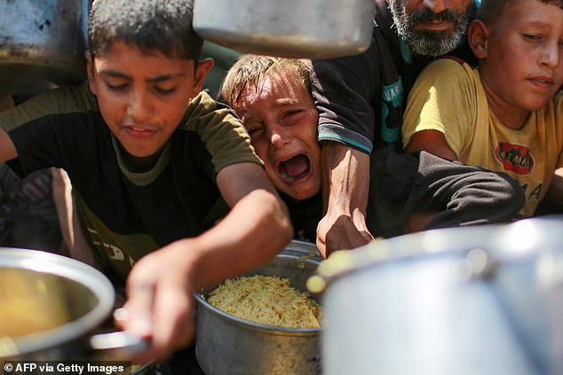 Na foto: Pessoas que tentam obter arroz de uma cozinha de caridade, fornecendo comida de graça no oeste da cidade de Gaza, em 28 de agosto de 2025