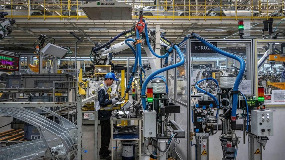Um trabalhador controla um braço robótico na linha de produção de uma fábrica de veículos elétricos em Ningbo, na China, a 29 de maio (Kevin Frayer/Getty Images)