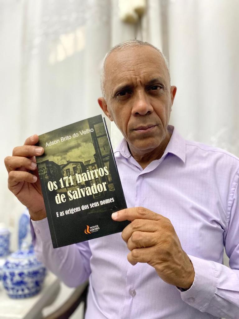 O escritor Adson Brito do Velho segurando seu mais novo livro, "Os 171 bairros de Salvador e as origens dos seus nomes". F