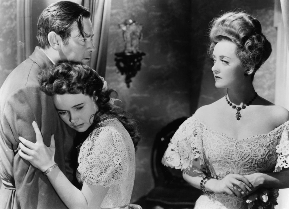 Com Herbert Marshall e Bette Davis (dir.) em cena de 'A loba' — Foto: Divulgação