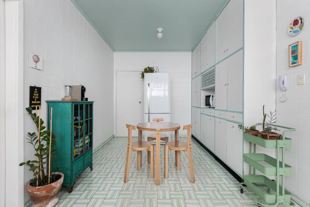 Apartamento tem teto amarelo e charmosa cozinha em tom verde menta. Projeto de Pro.a Arquitetos.