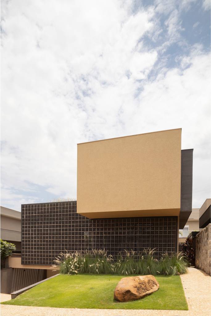 Casa moderna tem pedras rústicas de granito amarelo e cobogós na fachada. Projeto de WA Arquitetura.