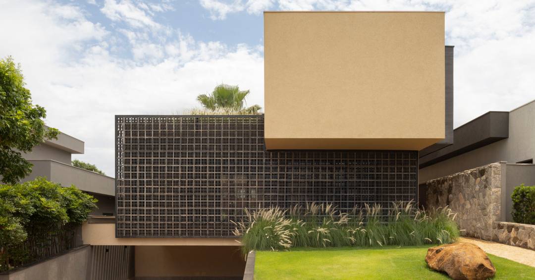 Casa moderna tem pedras rústicas de granito amarelo e cobogós na fachada