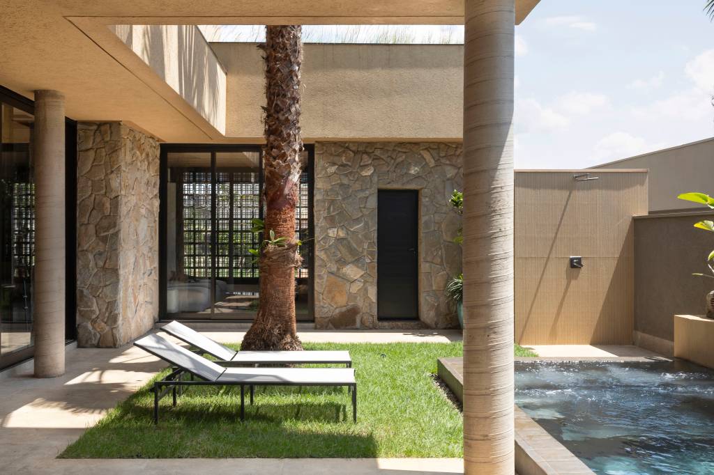 Casa moderna tem pedras rústicas de granito amarelo e cobogós na fachada. Projeto de WA Arquitetura.