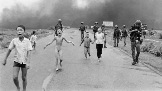 Forças sul-vietnamitas seguem crianças aterrorizadas, incluindo Kim Phuc, de 9 anos, ao centro, enquanto elas correm pela Rota 1 perto de Trang Bang após um ataque aéreo de napalm contra supostos esconderijos do Viet Cong, em 8 de junho de 1972.