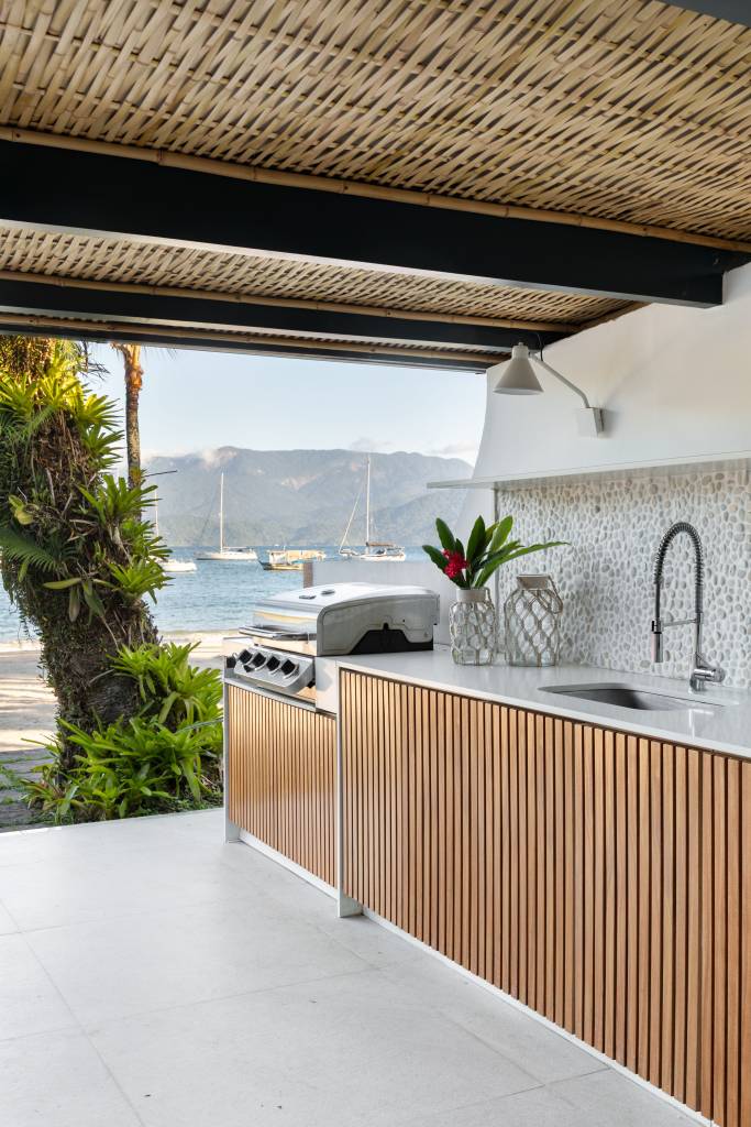 Telhado em bambu natural trançado cobre varanda gourmet de casa de praia. Projeto de A+G Arquitetura.
