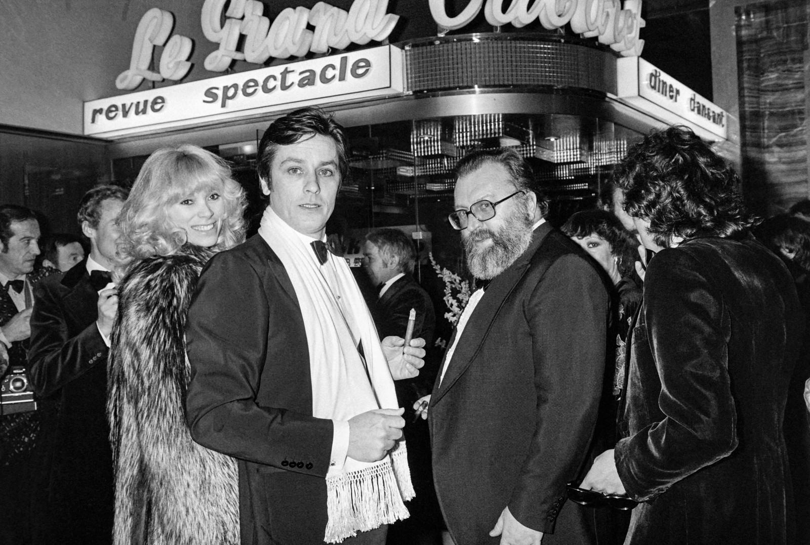 Alain Delon entre a atriz Mireille Darc e o diretor italiano Sergio Leone chegando à reinauguração da badaladíssima boate "Le Grand Cabaret", em 1977 em Nice, França — Foto: AFP