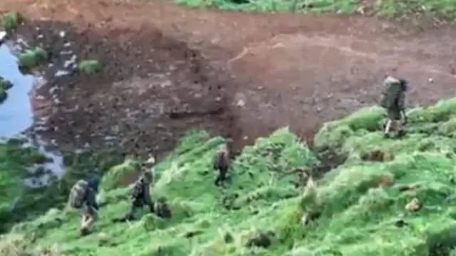 Filmagem de Phillips e três filhos caminhando sobre vegetação