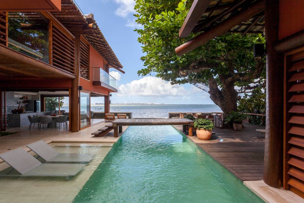 Casa de praia tem estrutura de toras de árvore e pergolados com esteiras em tala de dendê. Projeto de DB Arquitetos. Na foto, piscina.
