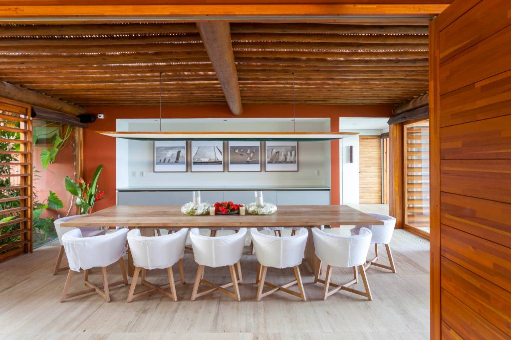 Casa de praia tem estrutura de toras de árvore e pergolados com esteiras em tala de dendê. Projeto de DB Arquitetos. Na foto, sala de jantar.