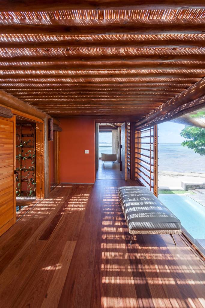 Casa de praia tem estrutura de toras de árvore e pergolados com esteiras em tala de dendê. Projeto de DB Arquitetos. Na foto, piscina, varanda.