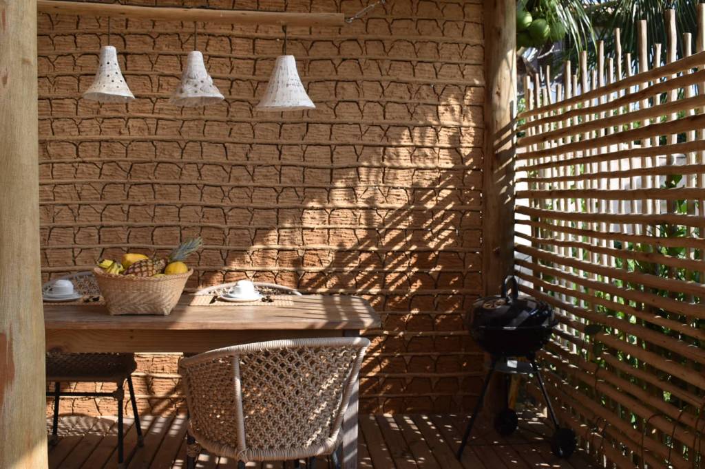 Casa pátio de praia na Bahia foi erguida em torno das árvores. Projeto de Mari Grobério. Na foto, varanda rústica, parede de taipa.