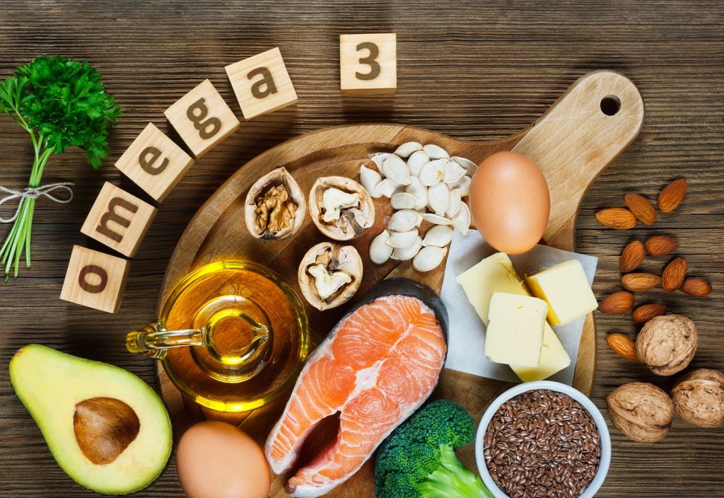 Variedade de alimentos ricos em ómega 3 sobre uma mesa de madeira.