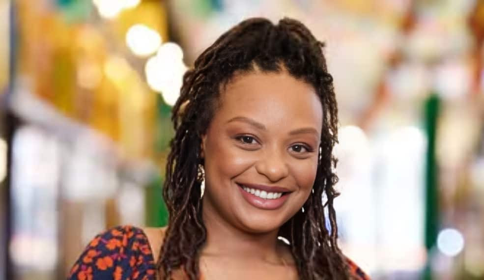 Haonê Thinar de vestido estampado e dreads, sorrindo para a câmera
