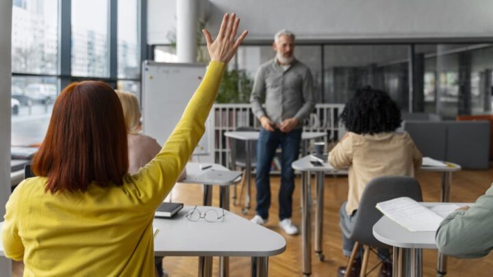 Estudante na sala de aula com o braço levantado
