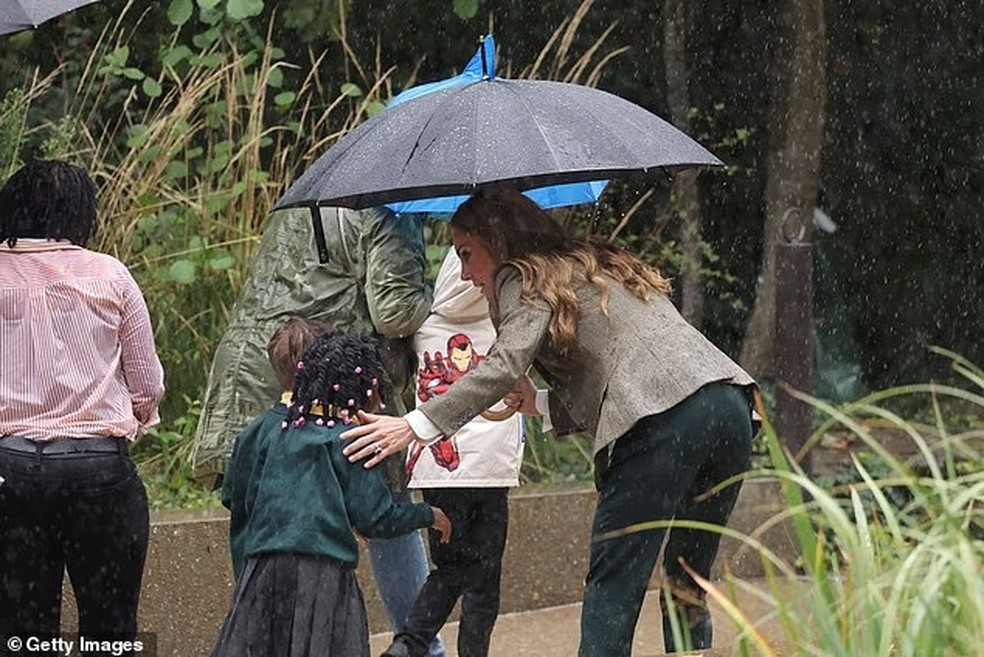 Kate Middleton ajudando criança na chuva — Foto: Getty