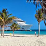 Praia paradisíaca no Caribe com areia branca, mar azul-turquesa, coqueiros e um navio de cruzeiro MSC ao fundo
