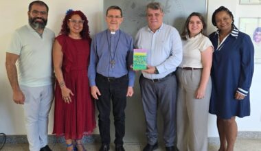 Foto dos participantes do encontro, com o reitor segurando o livro