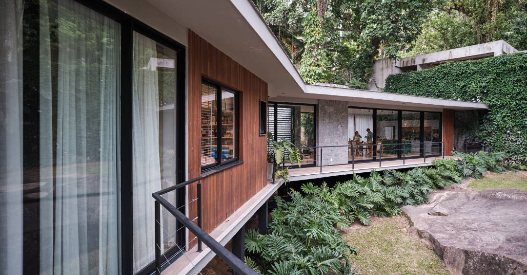 Árvore marca transição entre área social e íntima nesta casa no mato