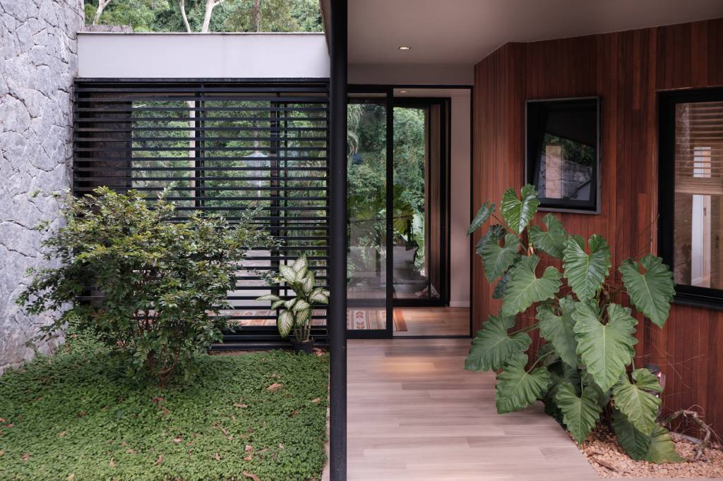 Árvore marca transição entre área social e íntima nesta casa no mato. Projeto de Thimi Arquitetura.