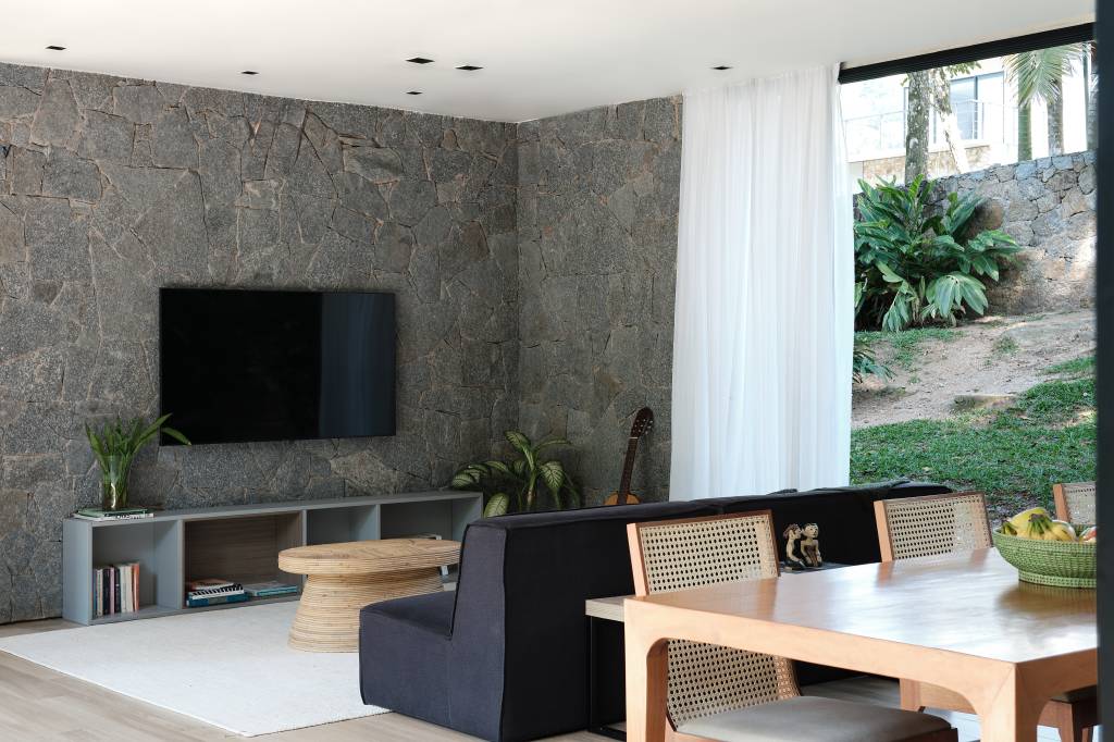 Árvore marca transição entre área social e íntima nesta casa no mato. Projeto de Thimi Arquitetura.