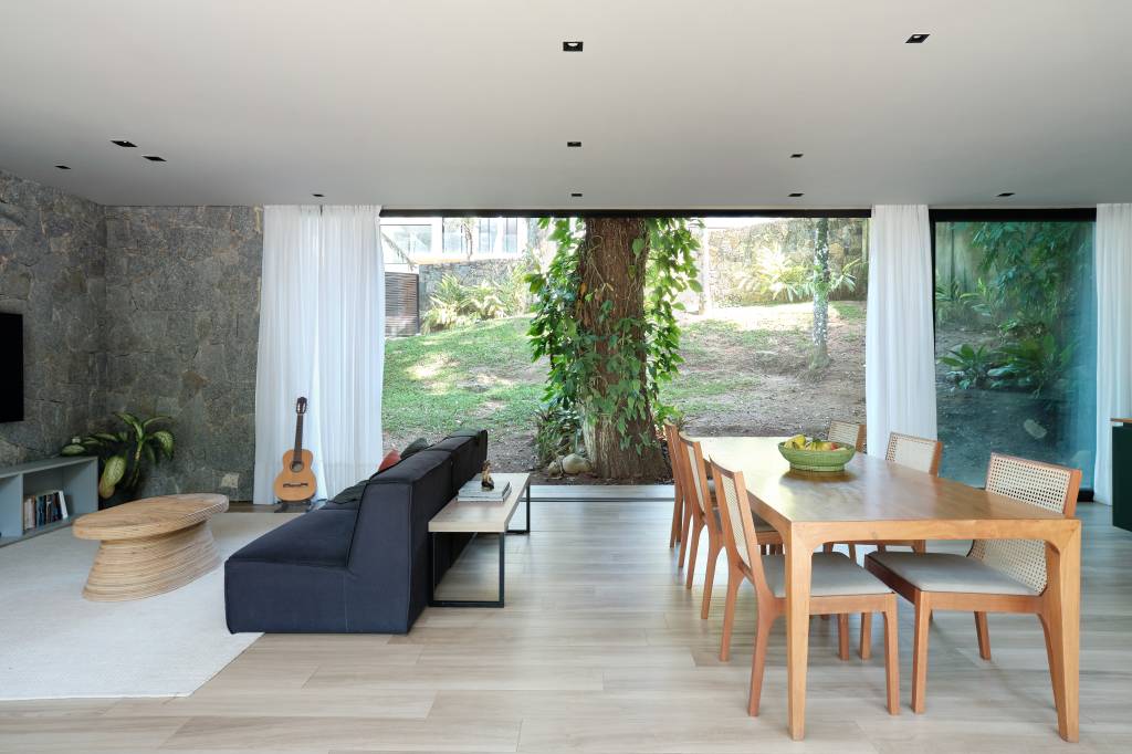 Árvore marca transição entre área social e íntima nesta casa no mato. Projeto de Thimi Arquitetura.