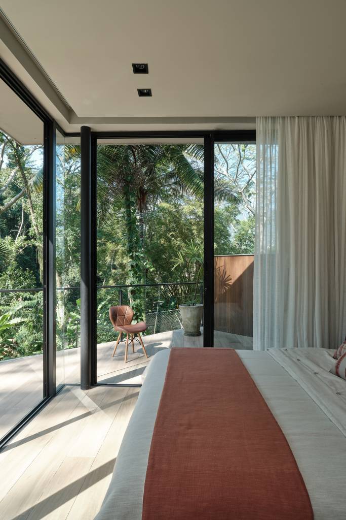 Árvore marca transição entre área social e íntima nesta casa no mato. Projeto de Thimi Arquitetura.