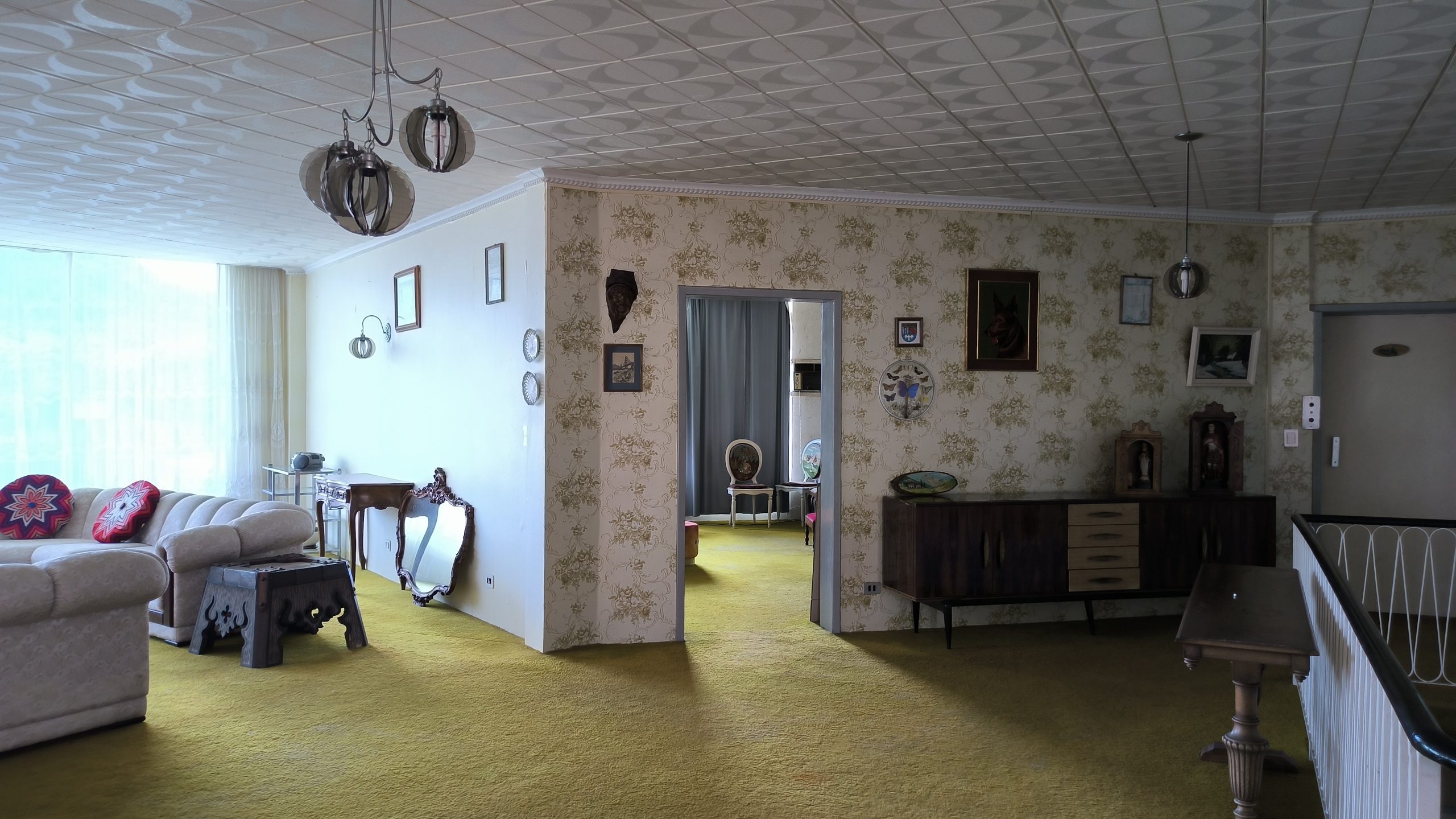 Sala de estar ampla com sofás, quadros, objetos decorativos e iluminação natural