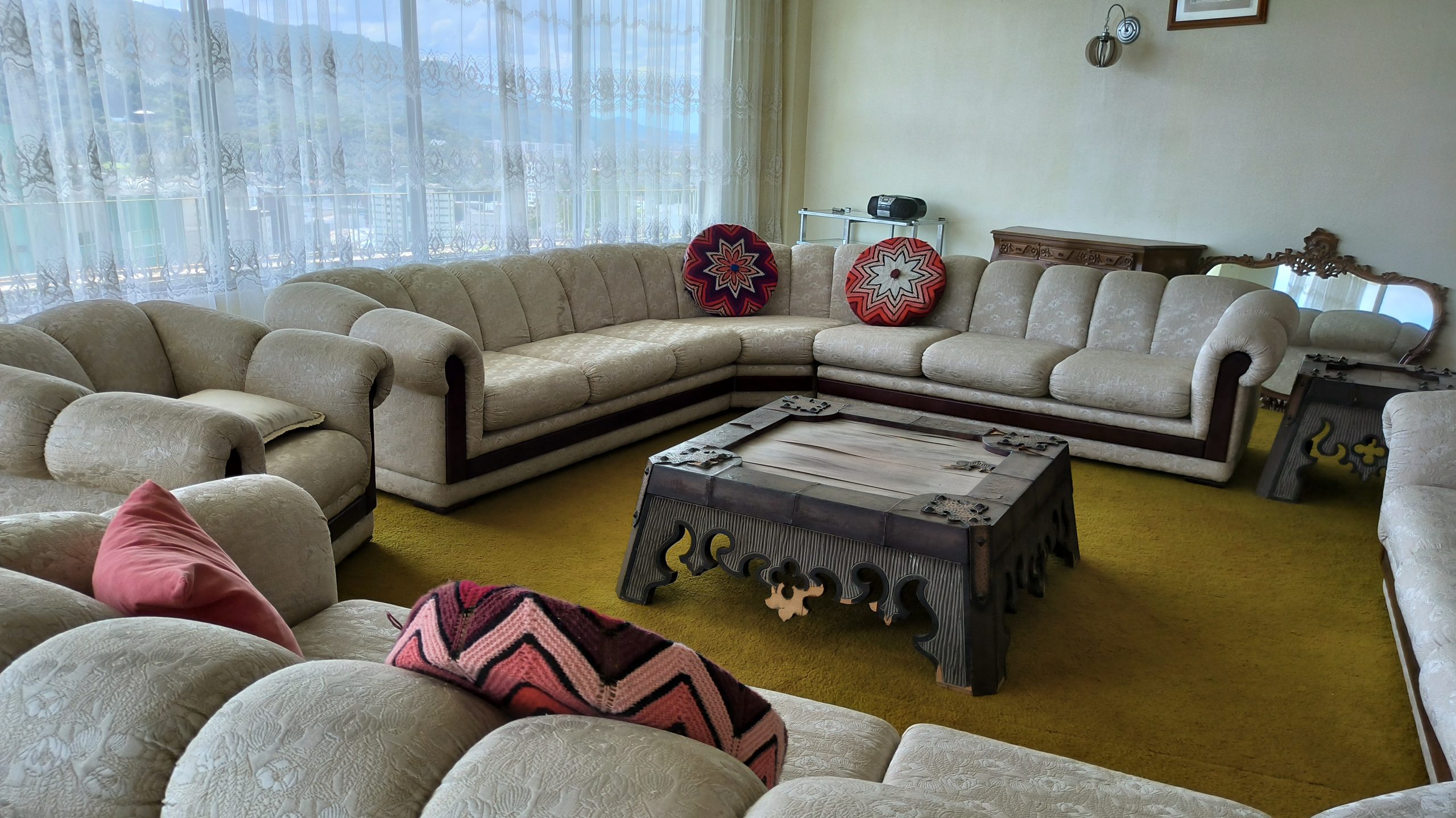 Sala de estar ampla com sofás, quadros, objetos decorativos e iluminação natural