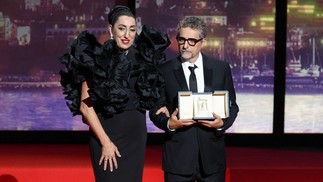 O diretor brasileiro Kleber Mendonça Filho recebe o prêmio de Melhor Ator em nome do ator Wagner Moura durante a cerimônia de encerramento da 78ª edição do Festival de Cannes, em Cannes, sul da França. — Foto: Foto: Valery HACHE / AFP