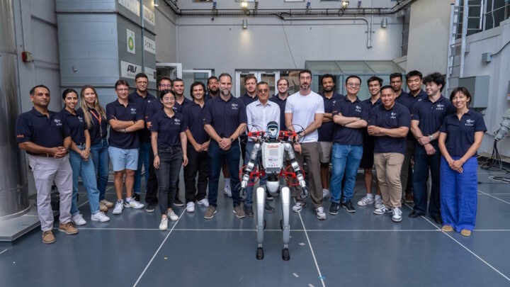 Robô humanoide X1 com o seu drone M4. Atrás deles, a equipa responsável