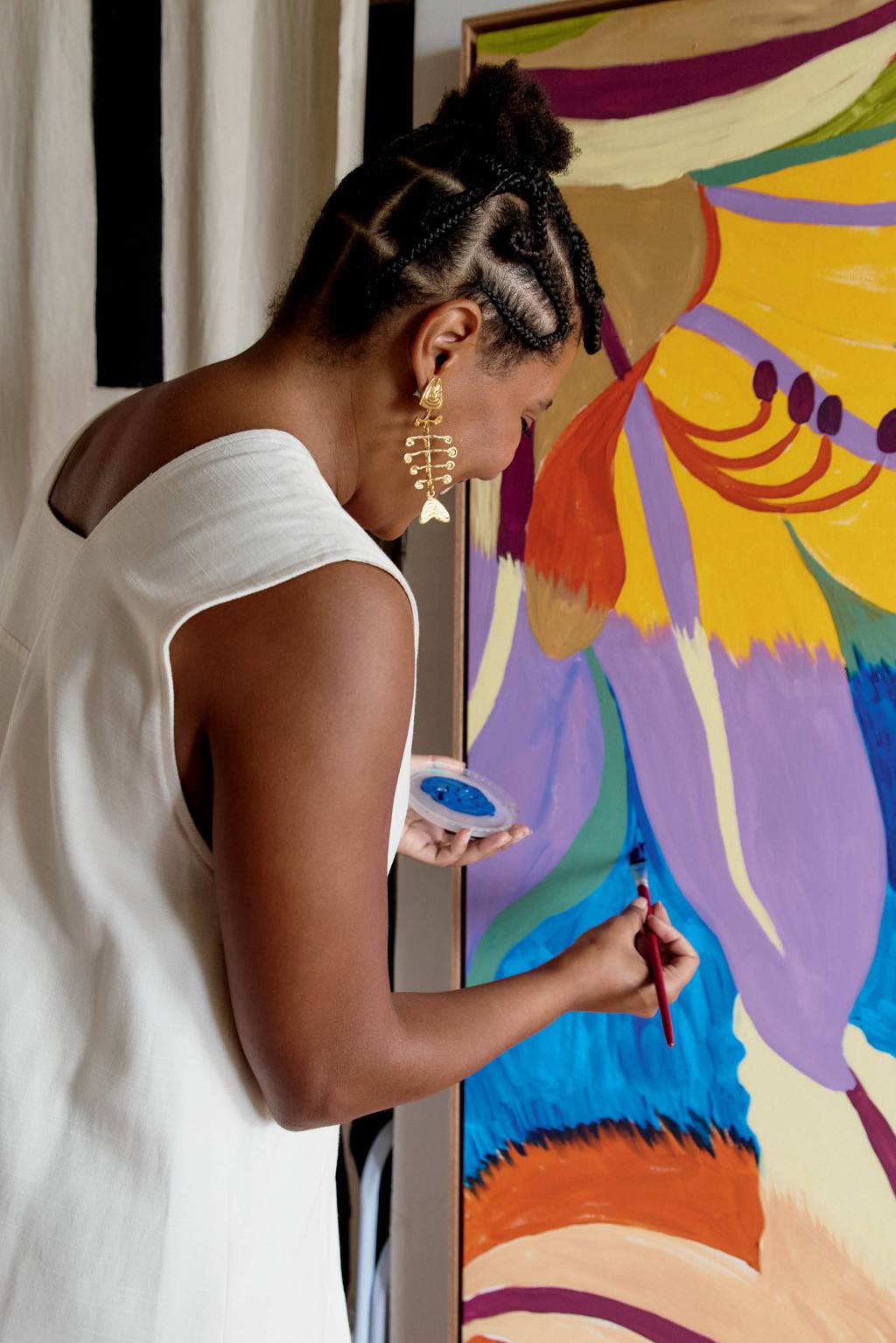 Mulher de costas pintando parede colorida.