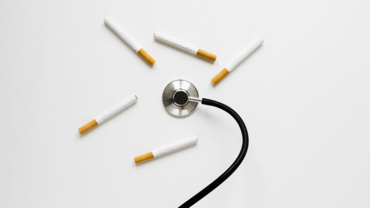 Estetoscópio rodeado de cigarros, num fundo branco