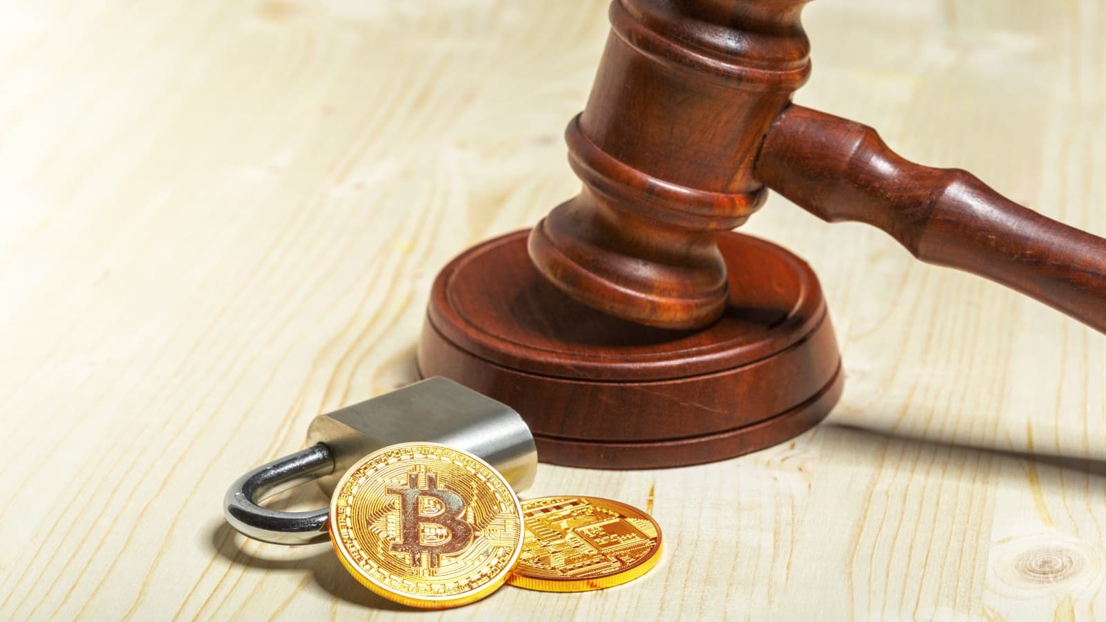 Duas moedas de Bitcoin, um cadeado e um martelo associado à justiça