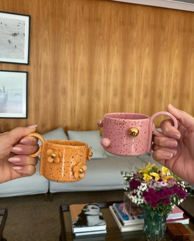 Mais detalhes da decoração, com mesa de centro, flores e livros— Foto: reprodução