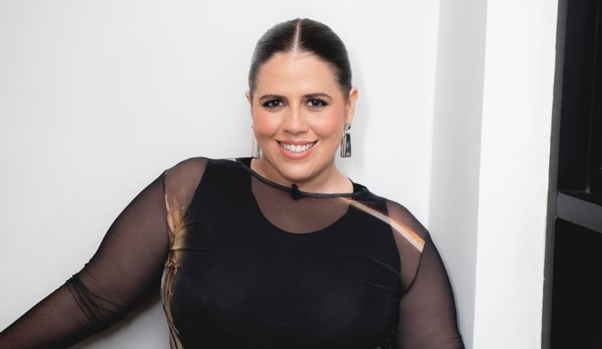 Tati Machado de roupa preta e cabelo solto, sorrindo para a câmera