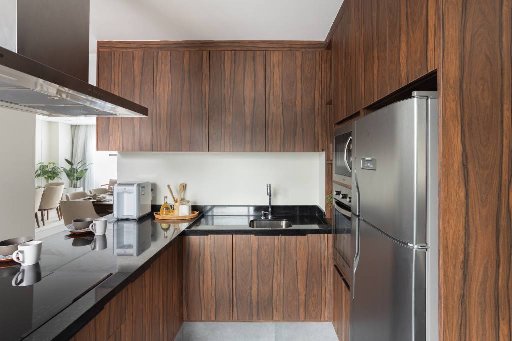 Marcenaria em pau-ferro percorre apartamento criando continuidade visual. Projeto de ResiliArt Arquitetura.