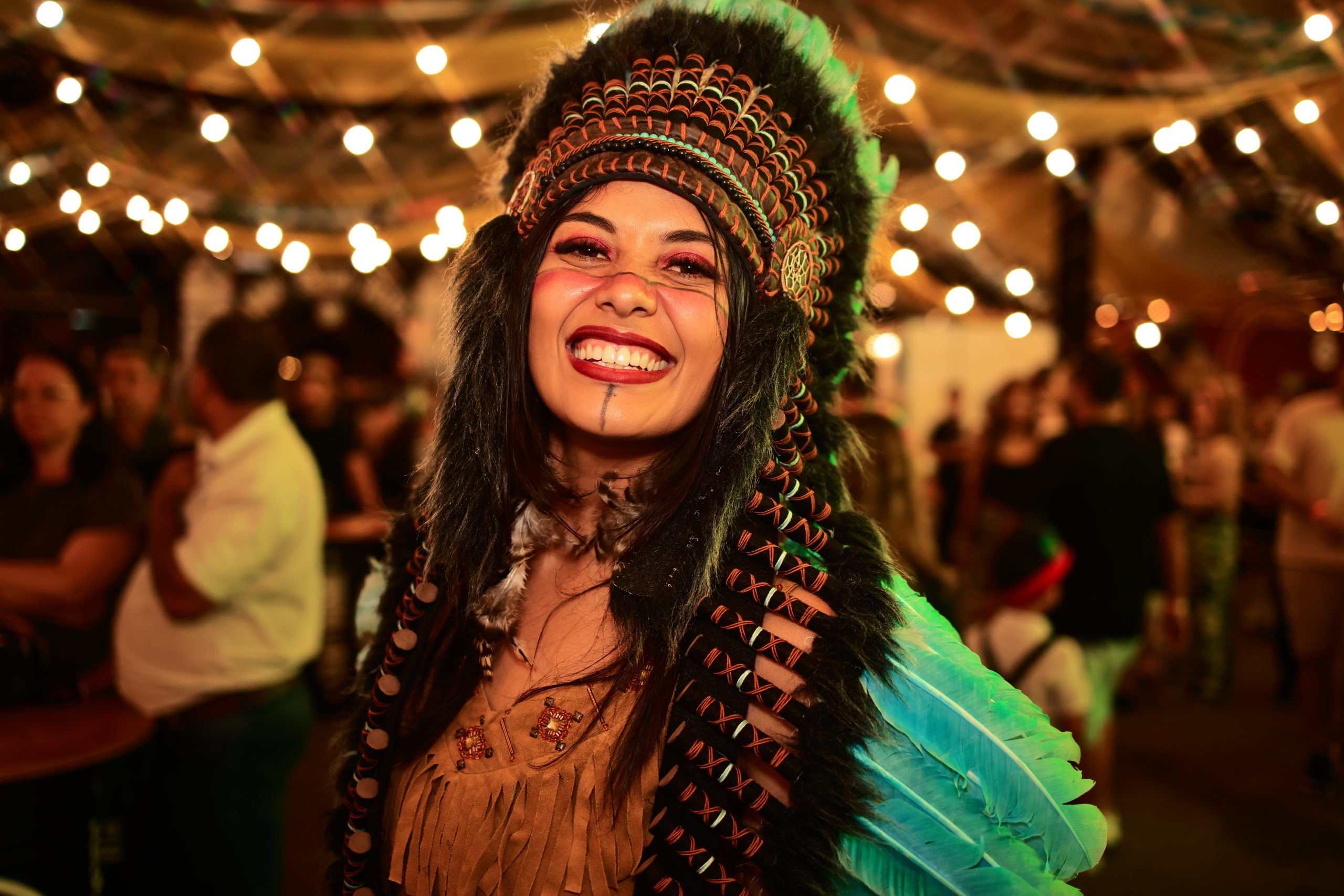 Mulher com cocar estilizado e pintura tribal sorri durante a Schützenfest