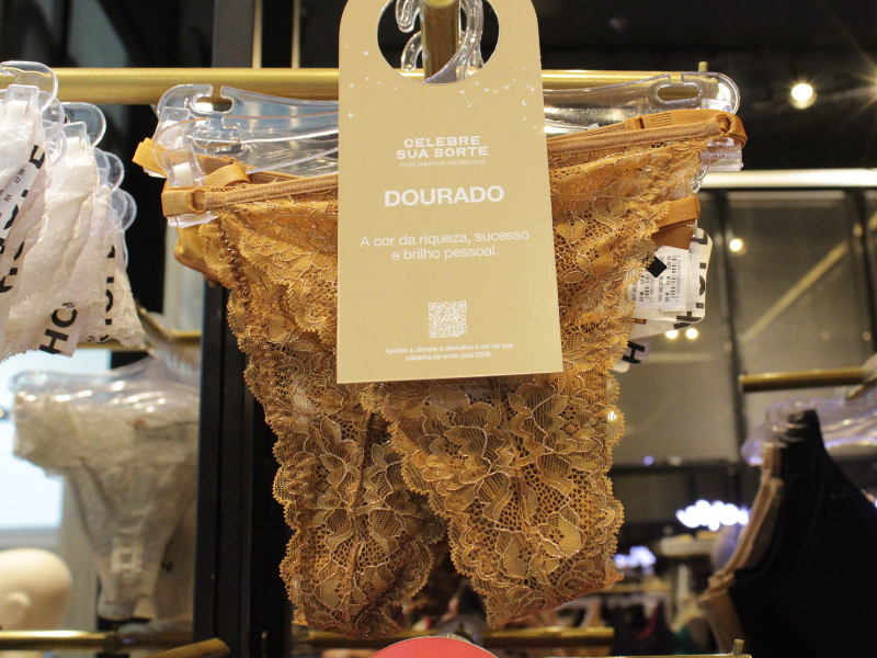 Calcinha de renda dourada com tag "Celebre sua Sorte", associando a cor à riqueza e ao sucesso.