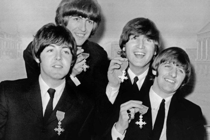 Nesta foto de arquivo tirada em 26 de outubro de 1965, a banda britÃ¢nica The Beatles (L-R), Paul McCartney, George Harrison, John Lennon, Ringo Starr segura seus prÃªmios MBE (Medalha do ImpÃ©rio BritÃ¢nico) em entrevista coletiva apÃ³s sua investidura no PalÃ¡cio de Buckingham em Londres -  (crédito: AFP / UPI PHOTO)