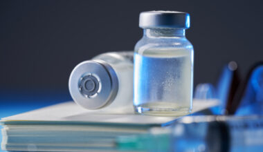 Frascos de injetáveis em cima de caderno e close-up de seringa desfocada