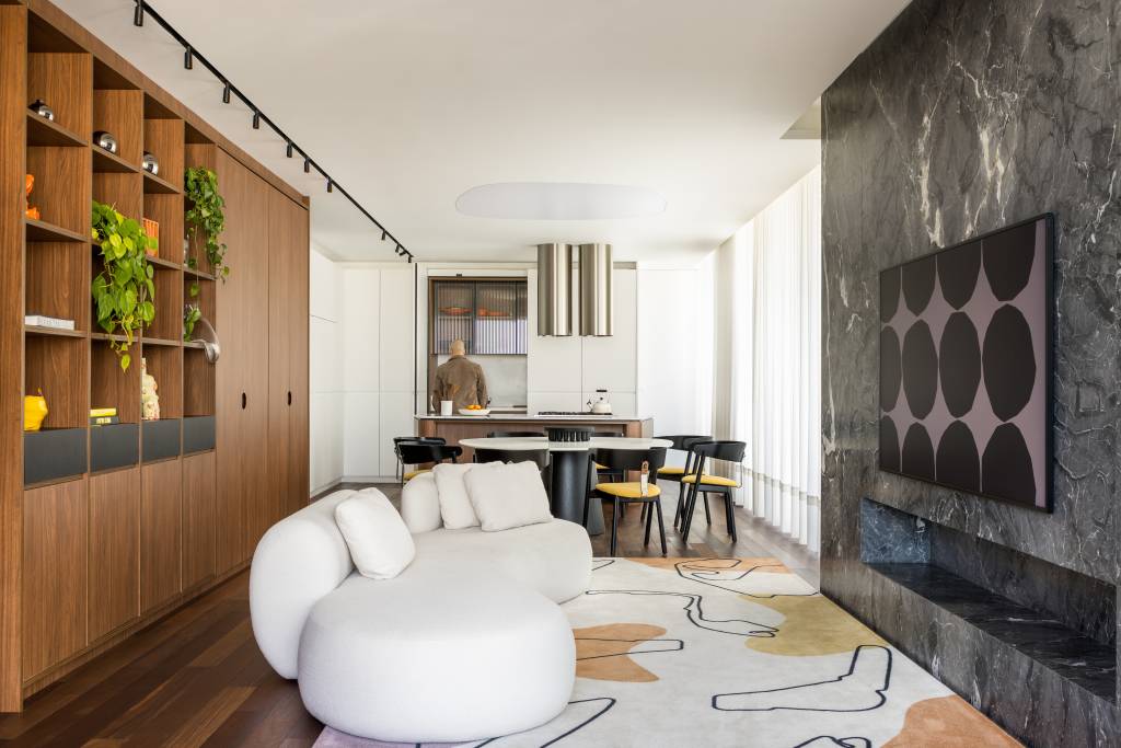 Faust Arquitetos – Fotos Eduardo Macarios (11) Ampla sala de estar integrada com cozinha com hack de madeira, parede de mármore verde e sofá branco