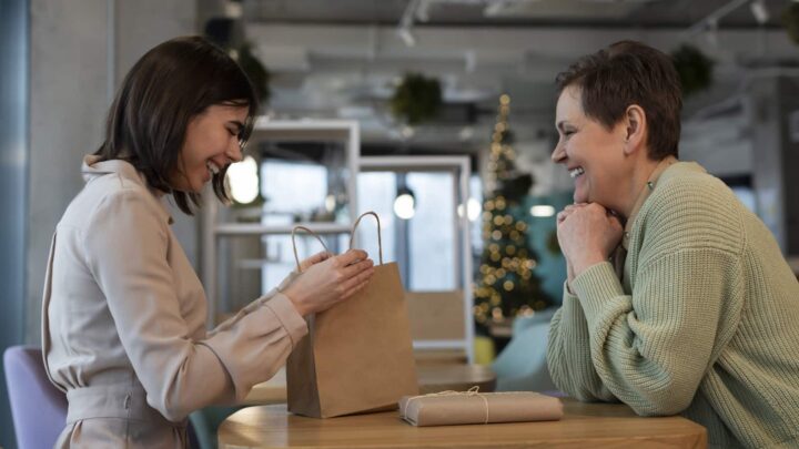 Duas mulheres frente a frente. A da esquerda segura um saco de papel