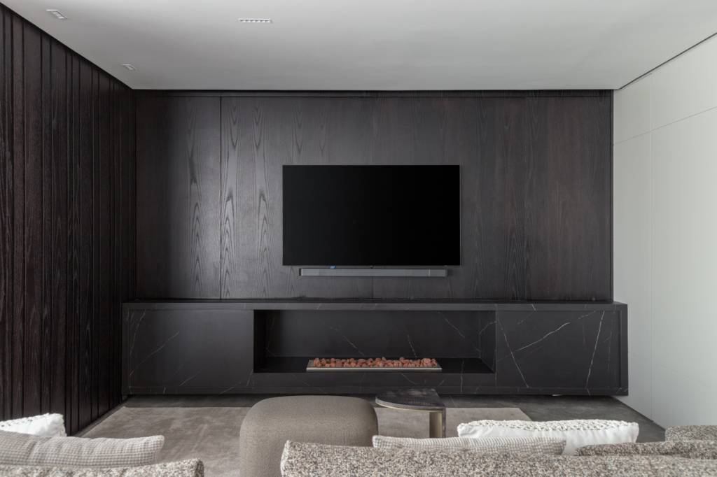 Elegância sóbria: tons de cinza e painéis de madeira ebanizada marcam apê. Projeto de Sabrina Salles.