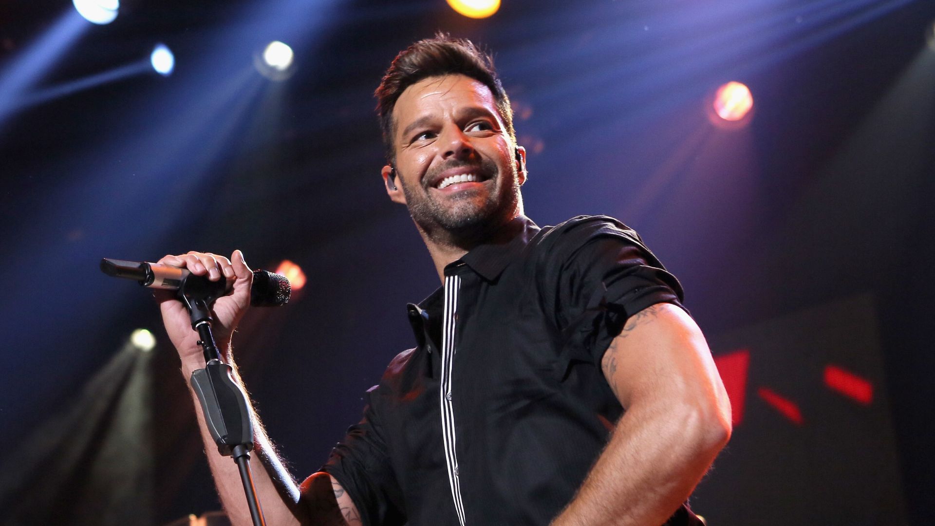 O cantor Ricky Martin em palco de apresentação; o artista comemora aniversário na véspera de Natal