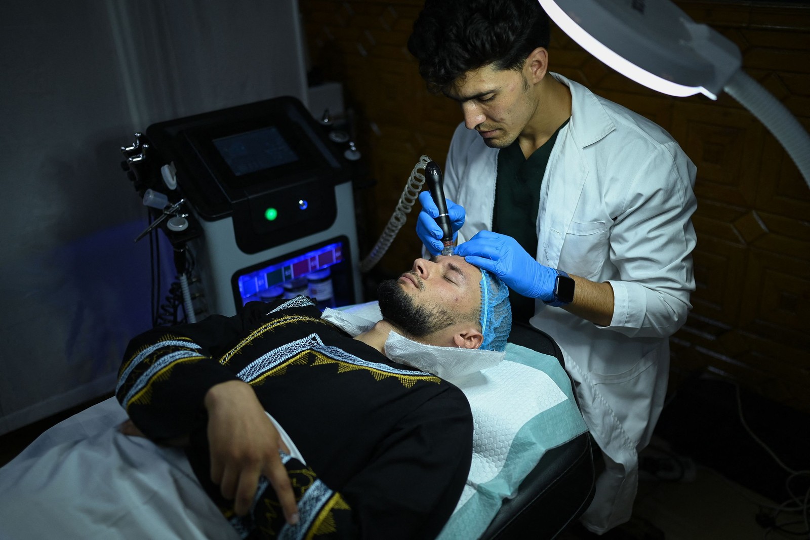 Membro da equipe médica realiza tratamento facial em um afegão — Foto: Wakil KOHSAR / AFP