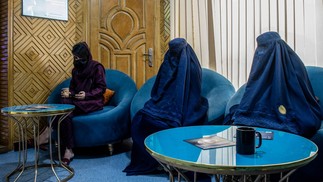 Mulheres afegãs vestidas com burcas, com consultas marcadas para tratamentos a laser, sentam-se em uma sala de espera em uma clínica de beleza em Cabul — Foto: Foto por WAKIL KOHSAR/AFP